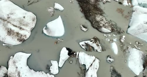 Große weiße Stücke schmelzenden Eises in der grauen Wasserlandschaft. Filmmaterial über dem See in Alaska, USA.