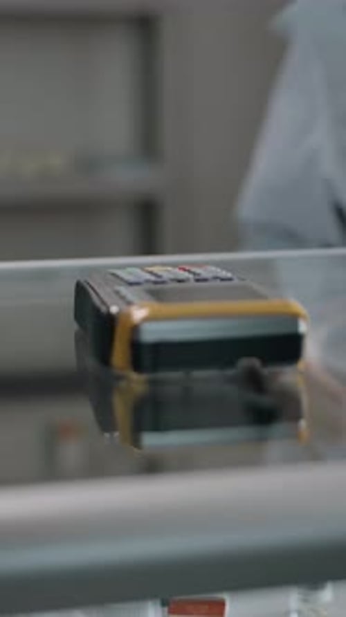 Vertical of A Man Pays for a Prepared Order at a Pharmacy By Credit Card on Terminal