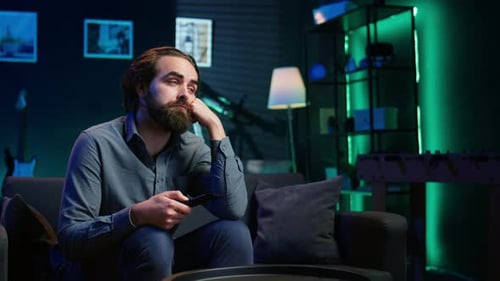 Close Up of Bored Man Sitting on Couch Flipping Though TV Channels