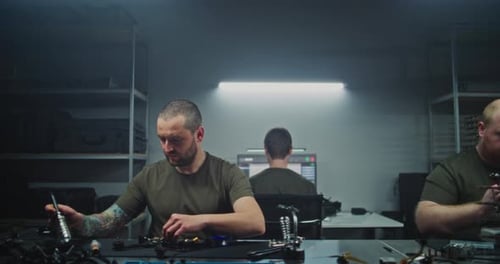 Engineer Stands Up From Workstation and Walks Through Drone Production Facility Passing Colleagues