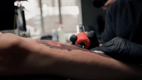 Close-up - the process of tattooing a woman on her leg. Male tattoo artist making a tattoo
