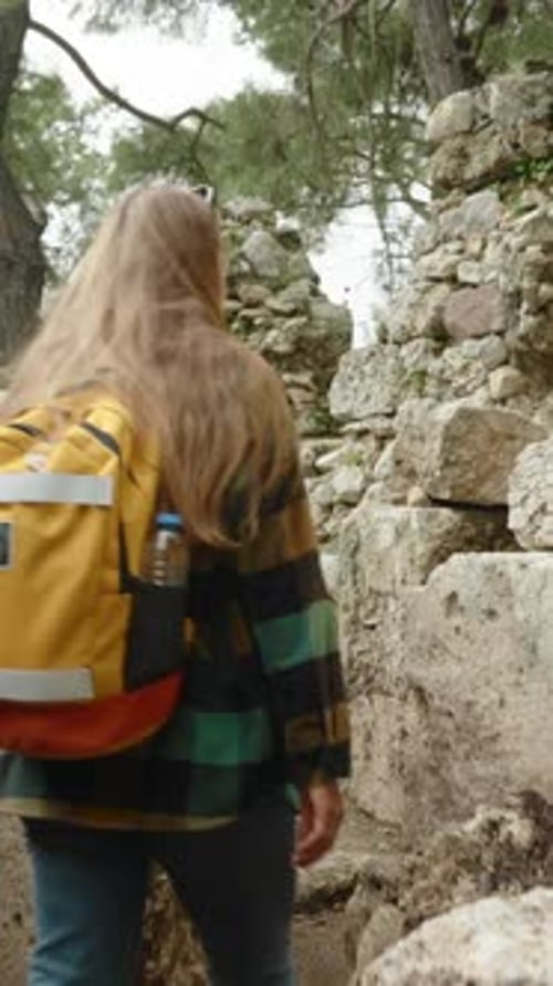 Woman Hikes Through Ancient Ruins in Forest