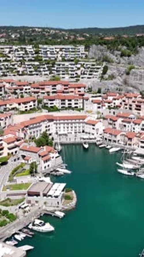 Drone survole la marina de Portopiccolo en direction du village, journée ensoleillée, vidéo verticale