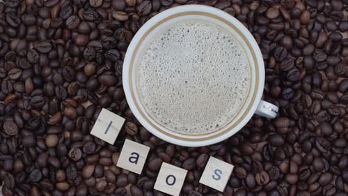 Top View of a Cup of Coffee on a Background of Coffee Beans with the Inscription Laos
