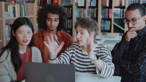 Group of College Students Discussing Project on Laptop in Library