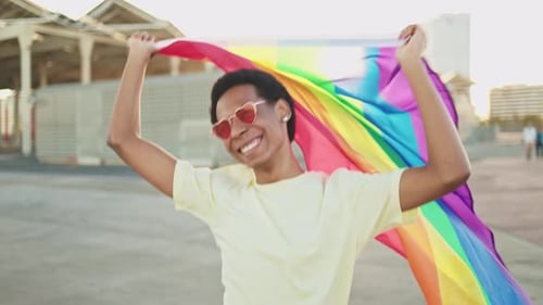 Upbeat Young Adult Waving Rainbow Flag