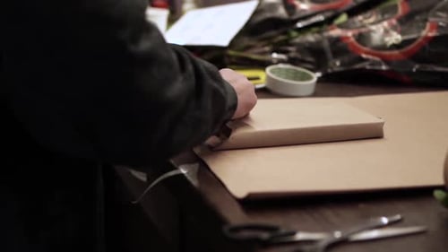 Person Wrapping a Box in Brown Paper