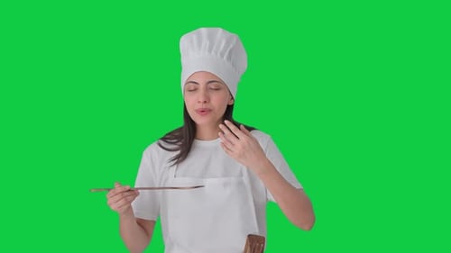 Happy Indian female professional chef tasting good food Green screen