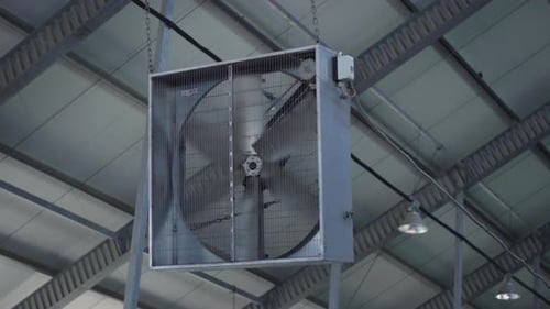 Gros plan d'un ventilateur industriel contrôlant la température dans une étable agricole moderne