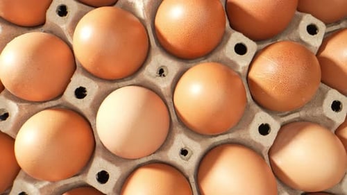 Farm-fresh eggs nestled in a rustic paper tray.