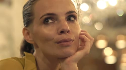 Pensive young woman sits alone in a blue lit cafe reflecting on life's difficulties