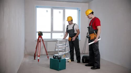 Wohnungsreparatur Zwei männliche Arbeiter schauen sich im Entwurf um