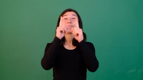 Smiling Woman Points Upward on Green Screen