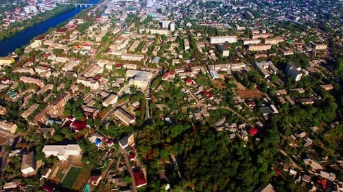 Densely built city landscape with lush greenery. Sunny view of the city on the river banks.