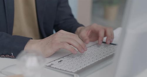 Closeup of Male Hands Typing with Computer Keyboard at Desk in Office