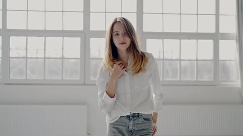Young Woman in White Shirt Posing Thoughtfully By Window