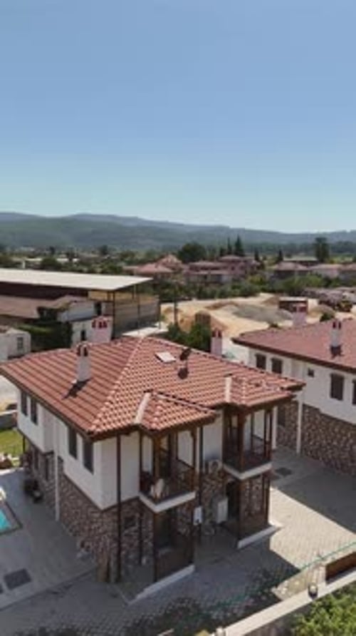 4K-Luftaufnahme von steinverkleideten Villen in einer malerischen Wohnanlage am Hang