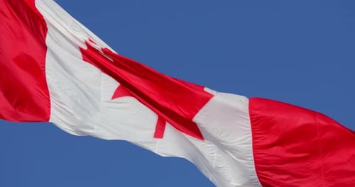 Canadian Flag Waving Proudly Against Blue Sky