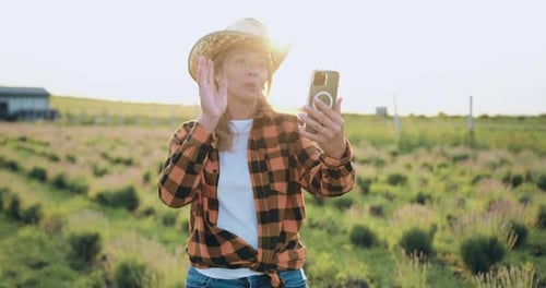 Hermosa granjera de mediana edad con sombrero tiene una conferencia en línea con socios de agronegocios