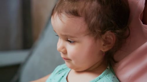 Adorable Infant Looking Away Indoors with Parent Nearby
