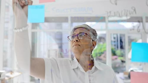 Woman Writes On See-Through Board At Office