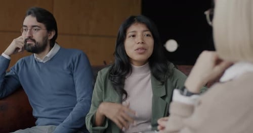 Unhappy Young Woman Talking to Therapist While Husband Listening Feeling Angry in Office