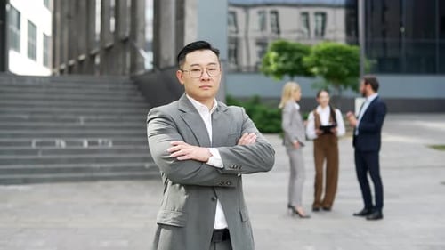 Portrait confident serious handsome businessman in suit standing looking at camera near office