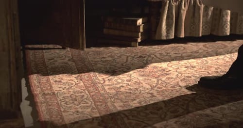 Men's black vintage shoes walk over an old carpet toward a wooden box, retro 1950s atmosphere.