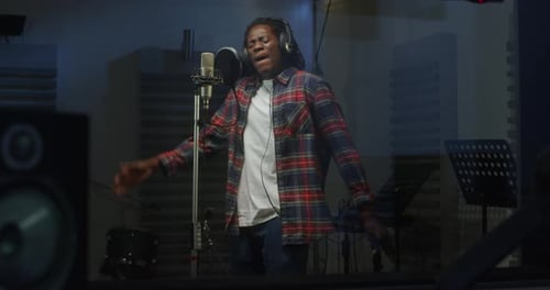 Portrait of Young Male Black Singer with Headphones Recording an Album in Professional Studio. Ex