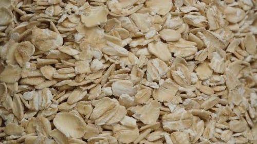 Filled transparent jar with oat flakes. Rotation close-up.
