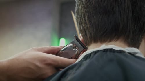 Hände eines Barbiers formen mit Haarschneidemaschine den Haarschnitt eines Mannes