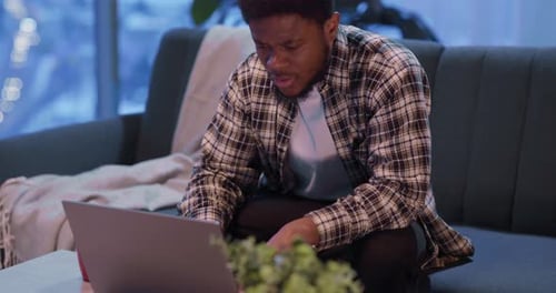 Young Adult Using Laptop on Couch at Home