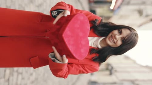 Smiling Woman Holding Heart Shaped Gift in City