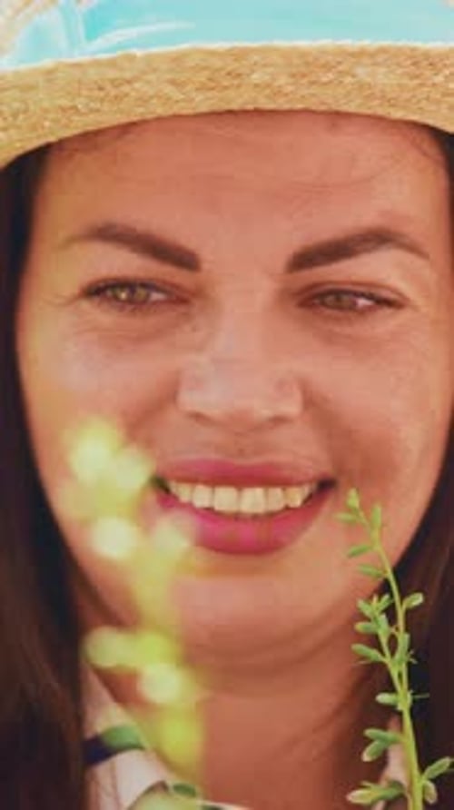 Une femme joyeuse coiffée d'un chapeau de paille sourit vivement au milieu d'un jardin coloré rayonnant de bonheur et