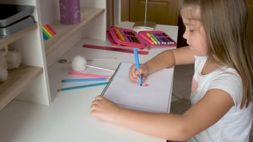Child Drawing with a Marker at Desk