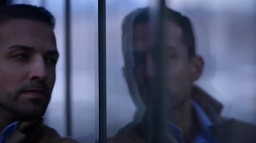 Man Gazing Thoughtfully at Reflection in City Window