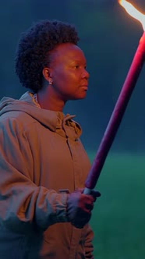 Young Adult Holding Flaming Torch at Night