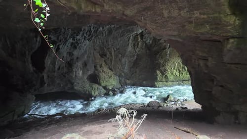 Wild river torrent flowing through the dark and rocky interior of the Tkalca Cave in Slovenia