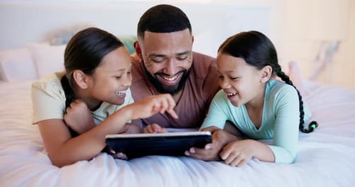 Father and Daughters Enjoying Tablet on Bed