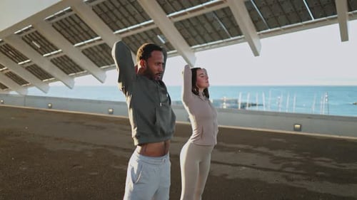 Active Couple Stretching Before Workout by the Sea