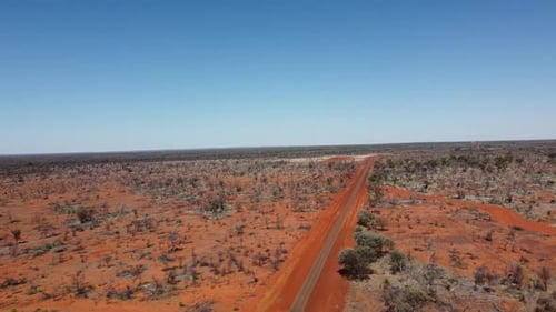 Drone flying towards a sealed road and unsealed road intersection in the Australian Outback