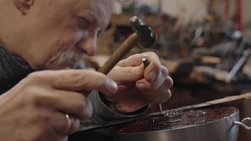 Elderly Master Craftsman on a Wheelchair Works in His Workshop Engraving Horimono Image on the Blade