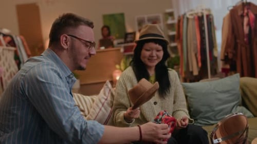 Diverse Friends Trying on Vintage Hats in Cozy Inclusive Secondhand Shop