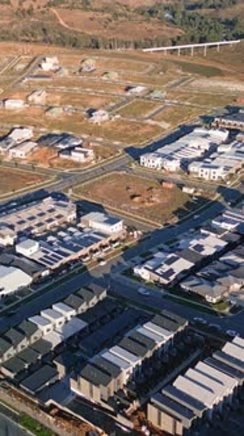 Vertical drone backwards revealing empty lots new houses solar panels Whitlam Canberra development