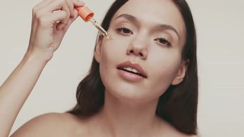 Woman Applies Serum to Face in Close Up