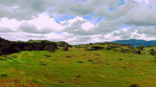 Black Rocky Green Grass Hills Windy Aerial Drone Footage on Cloudy Day revealing majestic mountains