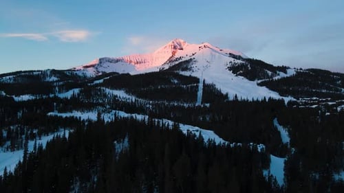 A drone shot of snowy Big Sky, Montana in winter, showcasing the ski resort and majestic mountain te