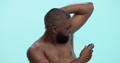 Happy man, deodorant and spray with bottle in studio for cologne or perfume on a blue background