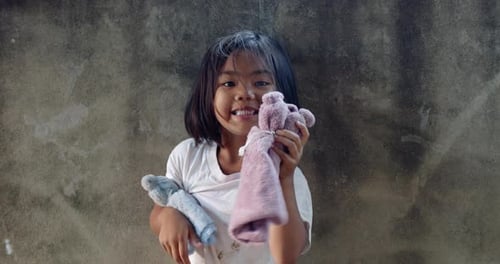 Une fillette asiatique de 5 ans originaire de la campagne thaïlandaise tient avec amour une poupée de bricolage fabriquée à partir de déchets de tissu