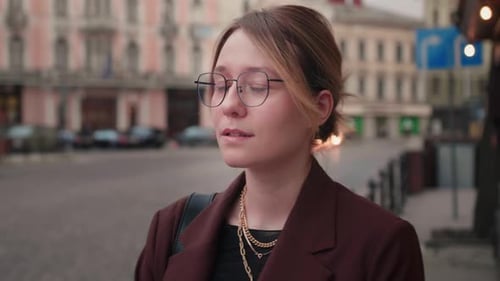 Portrait of Joyful Young Woman with Bright Hair and Glasses Standing Alone at City Smiling Looking